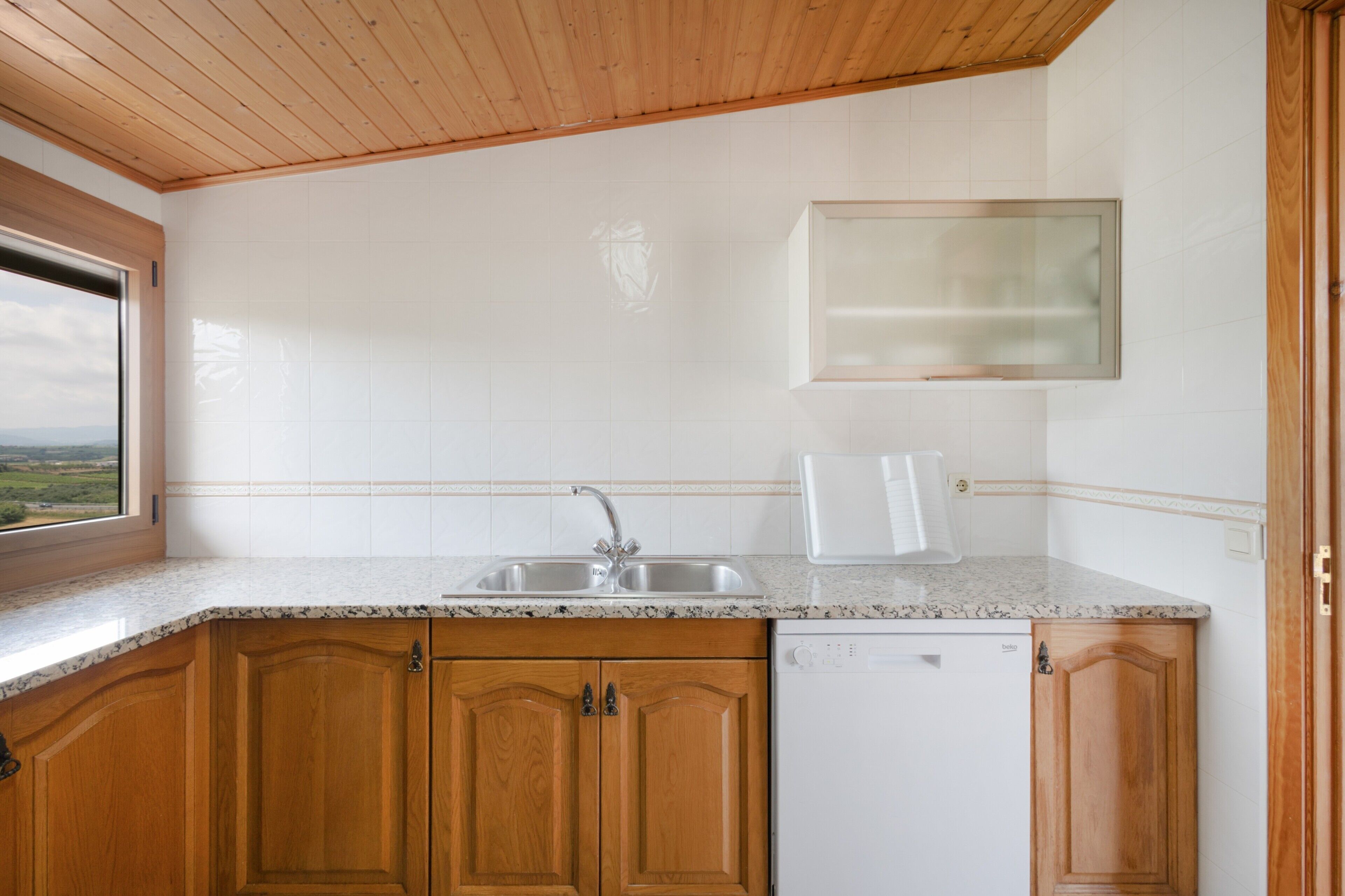 Una cucina con mobili in legno, un'lavastoviglie bianca e una finestra vista.