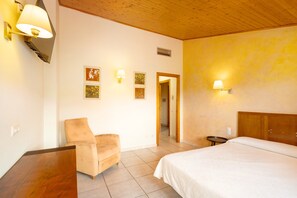 A bedroom with a bed, a chair, a small table, and wall-mounted lamps.