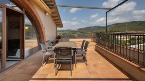 Un balcon avec une table et des chaises, une vue sur la campagne et un bâtiment à la façade en briques.