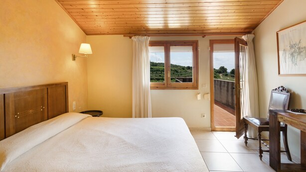 Une chambre à coucher avec un plafond en bois, un lit, un bureau et une vue par la fenêtre.