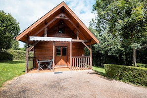 Une cabane en bois avec un balcon, une porte et une fenêtre.