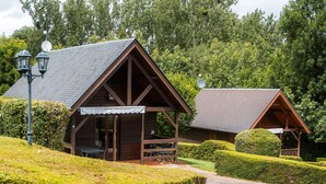 Une cabane en bois avec un toit en pente, une véranda avec des sièges et une antenne parabolique.