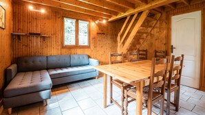 En inredning med träpanel, en soffa, ett matbord, stolar och en trappa.