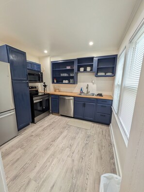 Eine moderne Küche mit blauen Schränken, Edelstahlgeräten und einer Holzausziehtafel.
