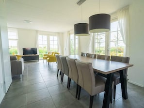 A spacious dining area with a long table and chairs, a sofa, and a TV in a corner. - Gulden Daalder Sauna 8 (Uitdam)