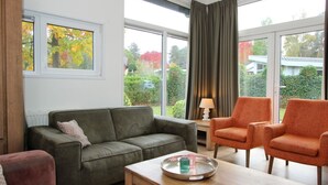 A living room with a sofa, two armchairs, a coffee table, and a lamp. - Holiday Home in Brunssum With Terrace (Brunssum)