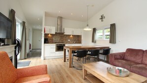 A modern living room with a sofa, a wooden coffee table, and a dining area with a table and chairs. - Holiday Home in Brunssum With Terrace (Brunssum)