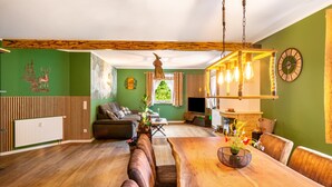 Een eethoek met een houten tafel, banken en een hanglamp.