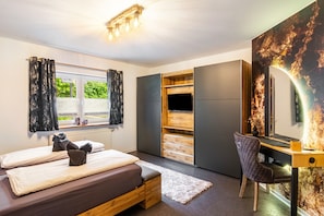Une chambre à coucher comprenant un lit, un bureau, une chaise, une armoire et un grand miroir.