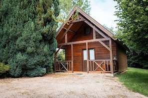 Una baita di legno con un portico, circondata da alberi fitti.