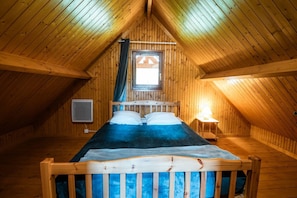 Una stanza in legno con un letto, una finestra e una TV a muro.