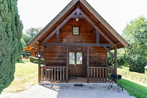 Eine Holzhütte mit Satteldach, einer Veranda und einer Tür mit Fenster darüber.