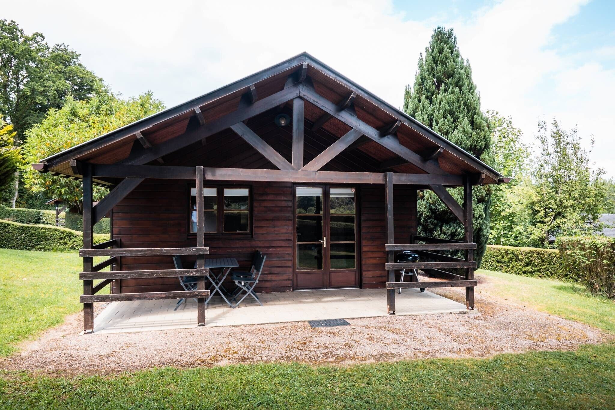 Eine Holzhütte mit überdachter Veranda, einem Tisch und Stühlen.