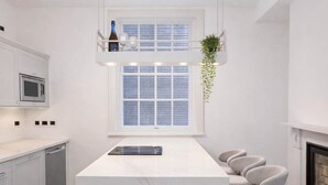 A modern kitchen with a central island, white cabinetry, a microwave, and a hanging plant. - The Bridge York - Stunning River Front Location (York)