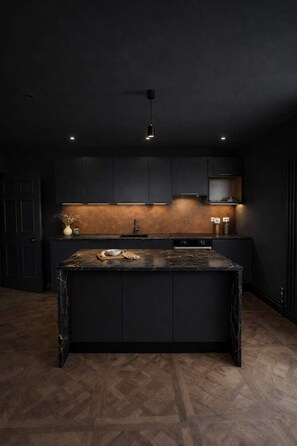 A modern kitchen with dark cabinetry, a central island, and under-cabinet lighting. - The Bridge York - Stunning River Front Location (York)