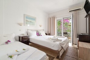A hotel room with two beds, a desk, a TV, and a balcony with flowers. - Room 'Double  117' with Shared Terrace, Wi-Fi and Air Conditioning (Nikiana)