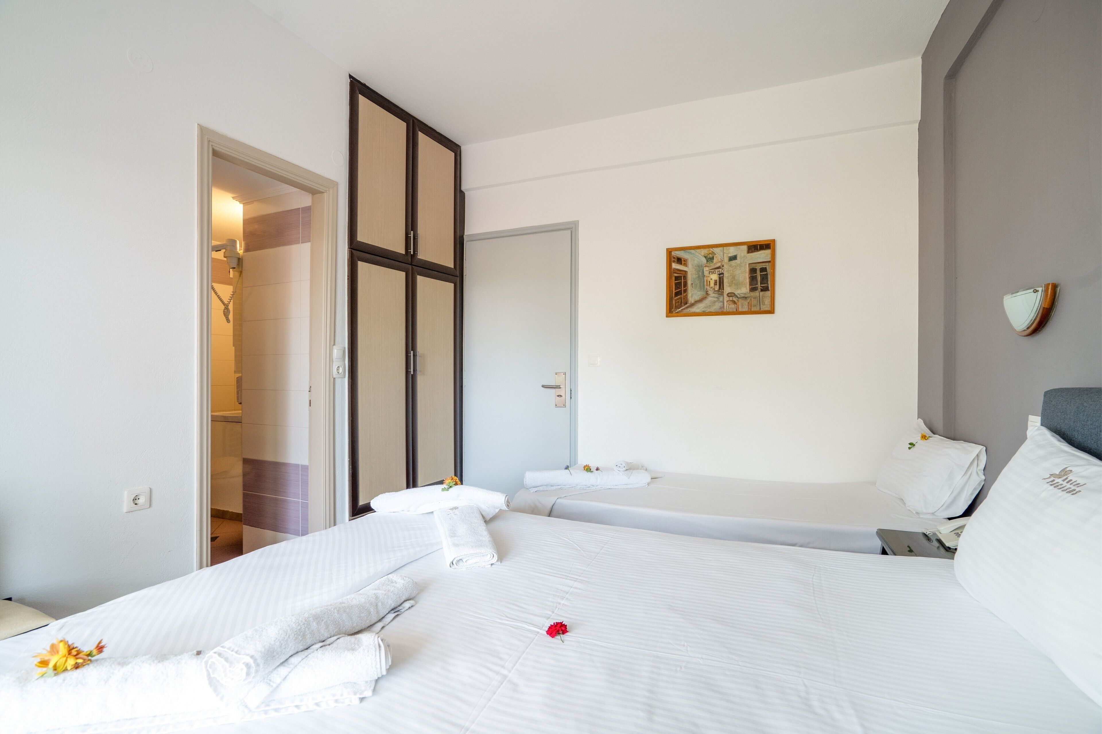 Hotelkamer met twee bedden, een douche, een schilderij aan de muur en een tafeltje met een telefoon.
