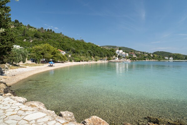 A coastal area with clear water, a stone pathway, and buildings on a hillside. - Room 'Double  118' with Shared Terrace, Wi-Fi and Air Conditioning (Nikiana)