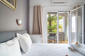 A bedroom with a bed, pillows, a bedside table, a window with curtains, and a view of the outdoors. - Room 'Double  118' with Shared Terrace, Wi-Fi and Air Conditioning (Nikiana)