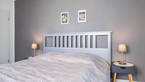 Ein Schlafzimmer mit einem Bett, zwei Nachttischen, einer Kopfteil und zwei Wandbildern.