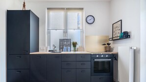 Eine moderne Küche mit einem schwarzen Schrank, einem Fenster, einer Uhr und einem gerahmten Bild an der Wand.