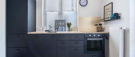 Una cocina moderna con un armario negro, una ventana, un reloj y un cuadro en la pared.