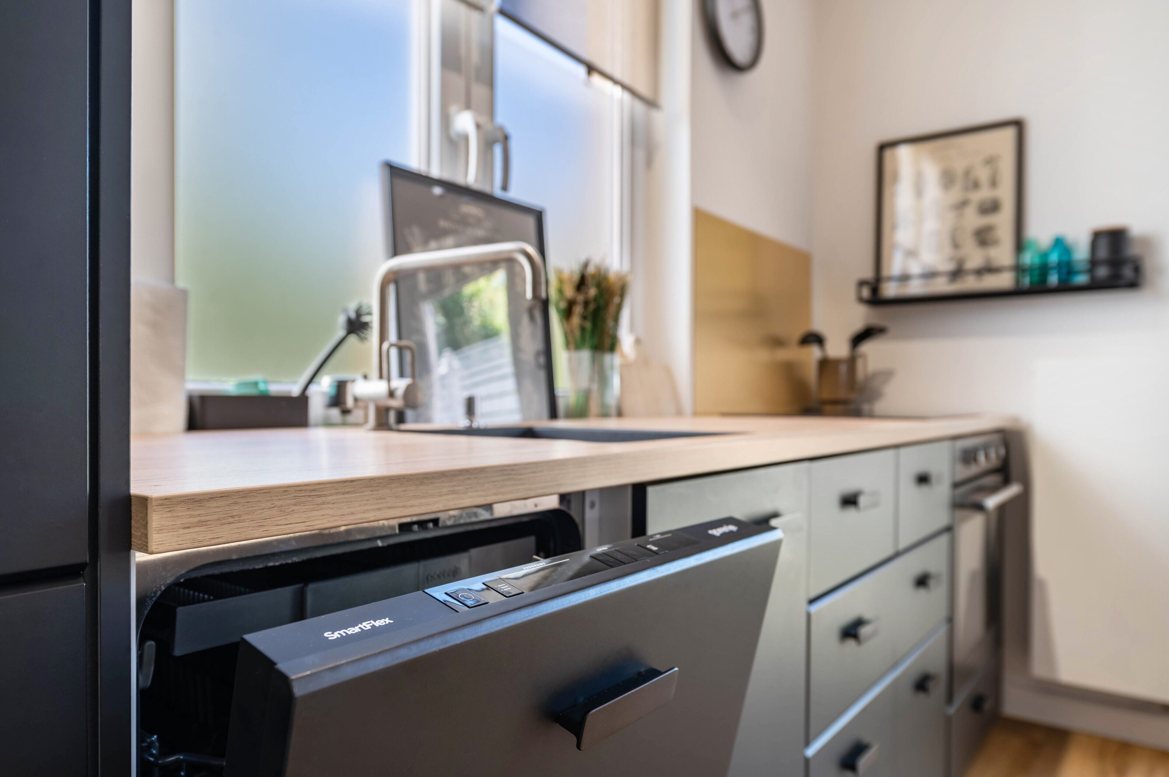 A modern kitchen with a dishwasher, a sink, and a window.
