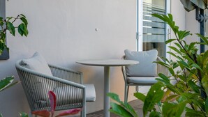 Eine Terrasse mit Korbstühlen und einem runden Tisch, eine Glastür zum Innenbereich und Kübelpflanzen.