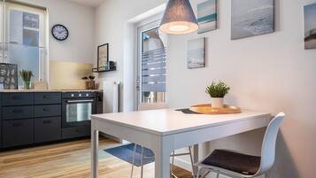Een moderne keuken met een witte tafel, een klok en een hanglamp.