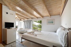 A bedroom with a bed, a TV, a small desk, and a balcony with a view. - Room 'Quadruple  405' with Sea View, Wi-Fi and Air Conditioning (Nikiana)