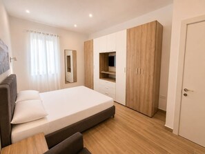 A bedroom with a bed, a wardrobe, a TV shelf, and a door. - Maisonette 2 Bedroom in quaint Qala with AC for relaxing stays next to Square (Qala)