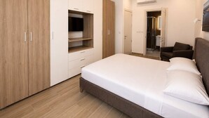 Quarto com cama, guarda-roupa, televisão e chuveiro.