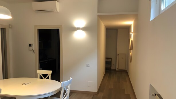 Eine kleine Küche mit einem runden Tisch und Stühlen, einem Einbauofen und einem Flur, der zum Schlafzimmer führt.