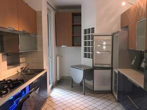 A compact kitchen with a gas stove, a built-in dishwasher, and a refrigerator. - ‘Papavero Porta San Agostino’ Apartment with Wi-Fi and Air Conditioning (Bergamo)
