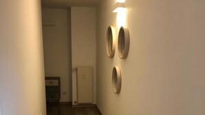 Ein Flur mit Holzboden, einer Tür am Ende und drei rundförmigen Wandspiegeln.