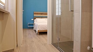 Une pièce avec un lit, un espace douche et un mur bleu.