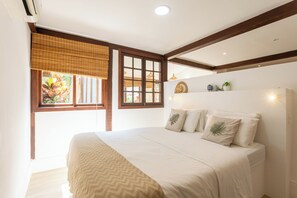 A bedroom with a bed, a window with blinds, a ceiling fan, and a wall-mounted shelf with decorative items. - On the edge of the lagoon-Gigóia Island: tranquility & nature next to the subway (Rio de Janeiro)