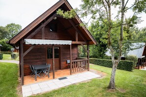 En stuga av trä med en veranda, ett bord och stolar.