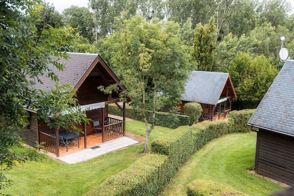 Deux cabanes en bois dotées de vérandas, entourées de pelouses bien entretenues et d’une végétation dense.