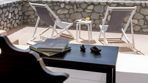 Un balcon avec deux chaises blanches, une petite table et un livre.