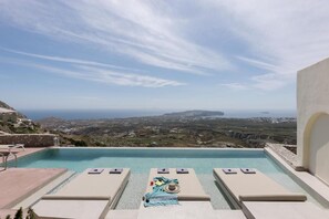 Une piscine avec des chaises longues et vue sur la côte.