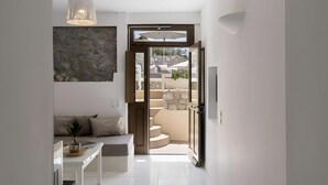 Un intérieur moderne comprenant un espace cuisine, un coin salon avec un canapé et une porte ouverte donnant sur un espace extérieur.