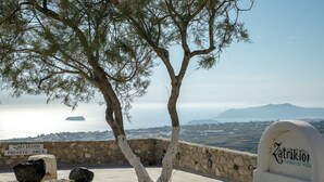 Un mur de pierre avec un arbre et une pancarte indiquant : « Zatrikion, villa de Santorin ».