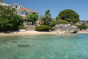 A coastal hotel with clear waters, a sandy beach, and a large rock formation. - Secret Beach B Apartment with Sea View, Wi-Fi, and Air Conditioning (Nikiana)