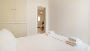 Ett hotellrum med en säng, en garderob och utsikt in i ett annat rum.