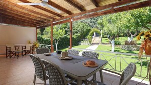 Une terrasse extérieure avec une table, des chaises et un ventilateur de plafond.