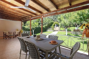 Eine Terrasse im Freien mit Tisch, Stühlen und Deckenventilator.