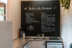 Eine Küche mit einer Kreidetafel, auf der ein Rezept für 'Moules à la Normande' steht.
