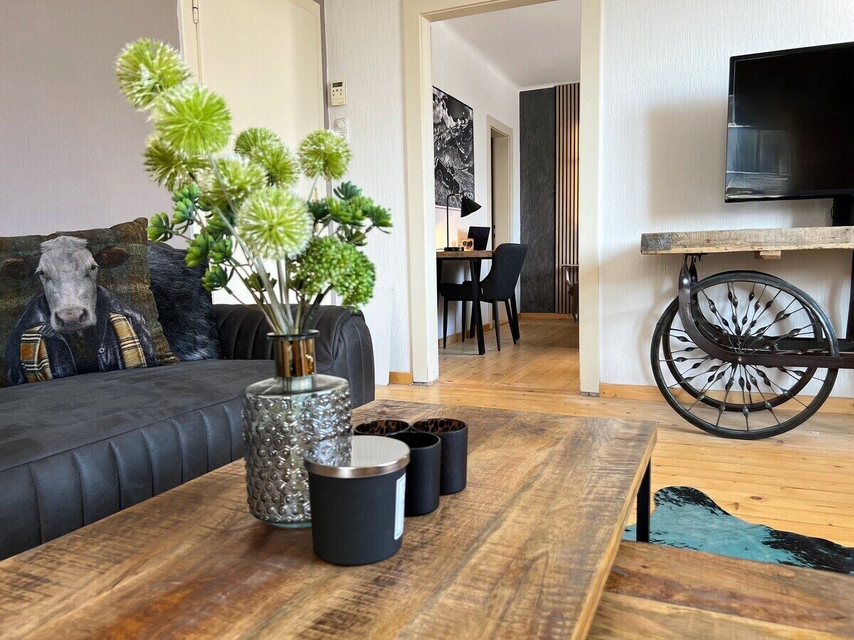 Ein modernes Wohnzimmer mit einer Couch, einem Couchtisch mit Dekoration, einem Fernseher und einem an der Wand befestigten Fahrradrad.