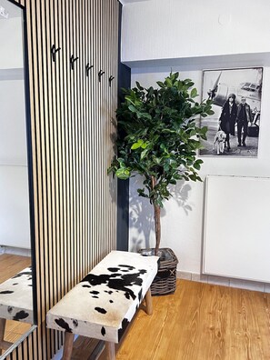 Ein Zimmer mit einer Wand aus vertikalen Holzleisten, einem Topfpflanzen, einer Sitzbank aus Rindsleder und einem schwarz-weißen Foto im Bilderrahmen.